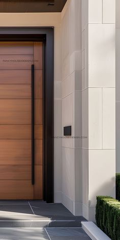 a large wooden door on the side of a building next to some plants and bushes