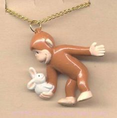 a necklace with a monkey holding a bunny on it's back and an egg in the other hand