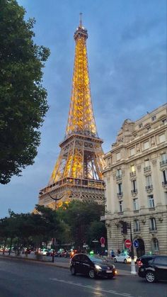 the eiffel tower lit up at night in paris, france with cars passing by