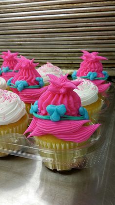 cupcakes with pink and blue frosting in plastic containers on a metal surface