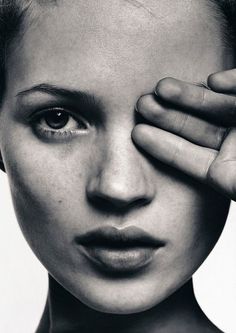 a black and white photo of a woman holding her hand up to her face with both hands