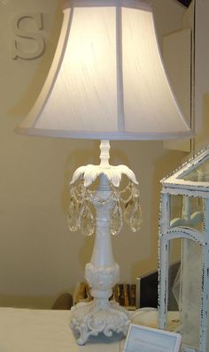 a white lamp sitting on top of a table next to a glass box and mirror