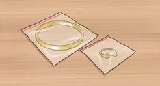 two napkins with rings on them sitting on top of a wooden table next to each other