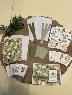 several cards and envelopes are laid out on a burlap surface with flowers