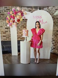 a woman in a pink dress standing next to two vases with flowers on them