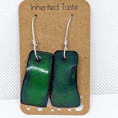 pair of green and black ceramic earrings with silver earwires on brown paper card