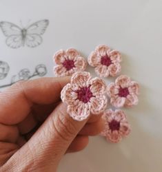 small crocheted flowers are being held by someone's hand on the table