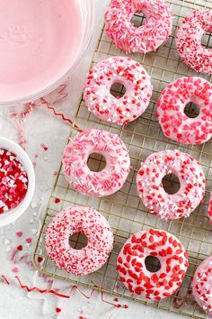 sprinkled donuts on a cooling rack with pink frosting and sprinkles