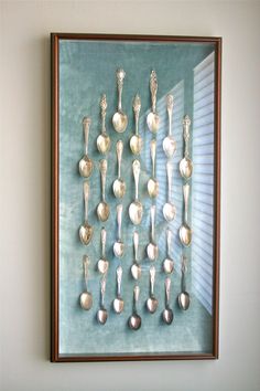 there are many spoons and spoons in this shadow box on the wall,