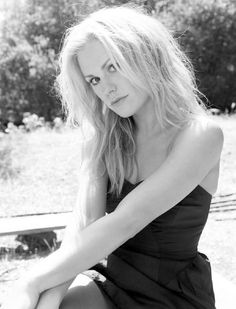 black and white photograph of a woman in a dress sitting on the ground with her legs crossed