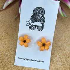 a pair of yellow flower earrings sitting on top of a card