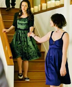 two women in dresses are walking down the stairs with their hands on each other's hips