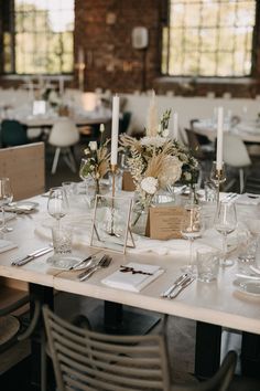 the table is set with place settings and flowers in glass vases on each side