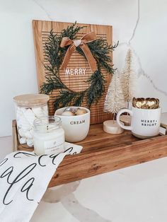 a wooden sign sitting on top of a counter next to two mugs and candles