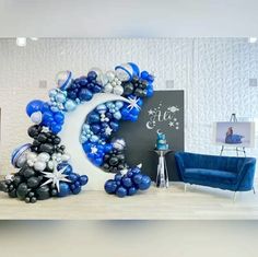 balloons are arranged in the shape of a crescent and stars on a white wall behind a blue couch