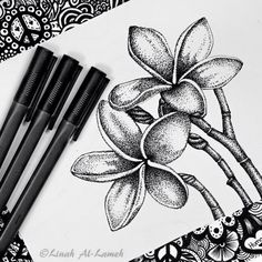 three black and white pens sitting on top of a piece of paper next to some flowers