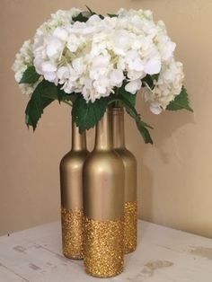 two gold vases with white flowers in them