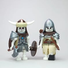 two lego figures with helmets and swords on their heads, one holding a shield and the other wearing a helmet