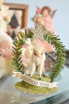 a christmas ornament on a glass table with angels and other ornaments in the background