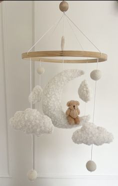 a teddy bear sitting on top of a cloud mobile