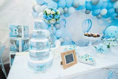 a baby shower themed dessert table with blue and white balloons on the wall behind it