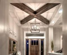 an entry way with a wooden door and chandelier hanging from it's ceiling