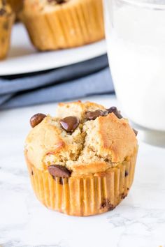 a muffin with chocolate chips on top and a glass of milk in the background