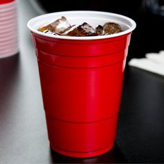 a red cup filled with ice sitting on top of a table