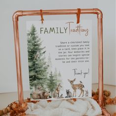 a family card with deers and trees on it, hanging from a copper frame