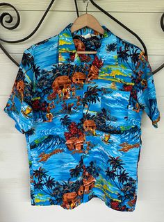 Vintage 1960's 1970's 'Styled in California' Hawaiian Printed Collared Shirt in * Button Down * Men's * Chest Pocket * Short Sleeved * Large * Vintage Hawaiian button down printed shirt * 'Styled in California' tag * Blue with multicolouring * Palm trees, sunset, flower, waves, ocean and people * Square front pocket * Collared * Short sleeved * Fabric feels lightweight * Fits like a men's large - XL Measurements (flat): Length: 29 in Left under arm to right across: 23.5 in Waist: 22 in Sleeve le Retro Hawaiian Shirt For Beach With Button Closure, Retro Hawaiian Shirt For The Beach, Retro Vacation Shirt With Button Closure, Retro Shirt With Button Closure For Vacation, Vintage Blue Collared Hawaiian Shirt, Retro Blue Button-up Hawaiian Shirt, Retro Blue Collared Hawaiian Shirt, Blue Retro Hawaiian Button-up Shirt, Vintage Beach Shirt With Buttons