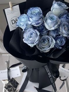 a bouquet of blue roses sitting on top of a black chair next to some tags