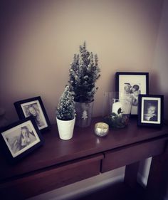 a table topped with pictures and a potted plant next to two framed photos on it