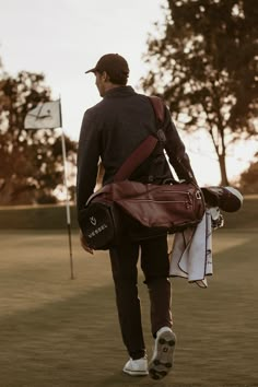 a man walking across a field carrying a bag