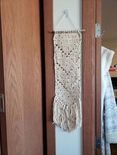 the door is open and there is a crocheted wall hanging on the side