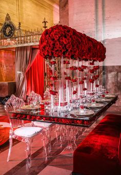 a long table with red roses on it is set up for a formal dinner or party