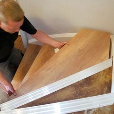 a man that is kneeling down with some wood in his hand and looking at the floor