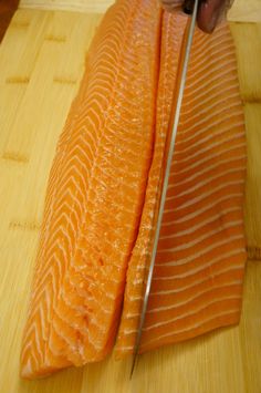 a person cutting up a fish on top of a wooden table