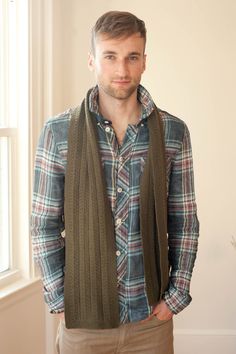 a man standing with his hands in his pockets and wearing a scarf around his neck