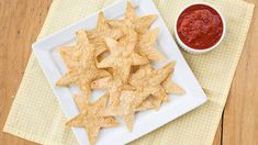 a white plate topped with star shaped crackers next to a small bowl of salsa