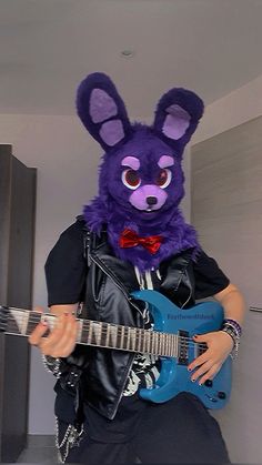 a man in a purple bunny mask plays an electric guitar