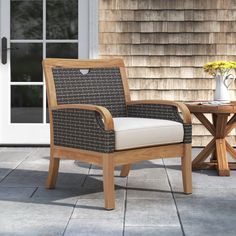 a wooden chair sitting on top of a patio next to a table with flowers in it