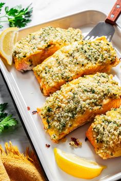 baked salmon fillets on a plate with lemon wedges and parmesan cheese