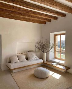 a living room with white furniture and wood beams on the ceiling, along with a large window