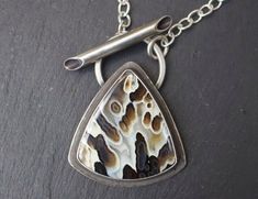 "This Pendant features a Rare Black and White Tube Agate in a Sterling Silver setting with a hollow and beveled Toggle. It hangs from a Sterling Silver oval link chain. Chains can be cut between 15-20\" just message me the length you would like. It connects with hand made bench hardened Hook and Loop Clasp." Tube Setting, Silver Necklace Designs, Modern Silver Jewelry, White Tube, Handmade Pendant Necklace, Metalwork Jewelry, Metalsmithing Jewelry, Fossil Jewelry, Art Jewelry Contemporary