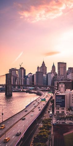 an aerial view of a city and the water at sunset with traffic driving on it