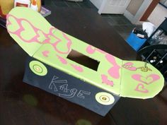 a cardboard box shaped like a skateboard with pink and green designs on it's side