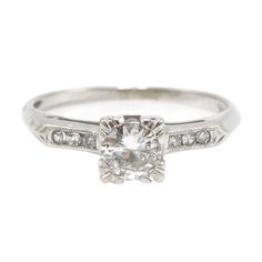 an antique style engagement ring with diamonds on the sides and a center stone in the middle