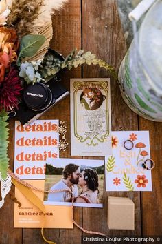 an assortment of wedding stationery items on a wooden table with flowers and other things