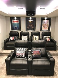 a home theater with black leather recliners and pictures on the wall above them