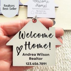 a person holding a house shaped keychain with the words welcome home on it